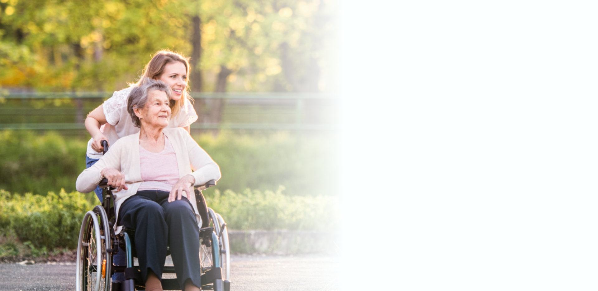 Elderly grandmother in wheelchair with granddaughter in spring nature.