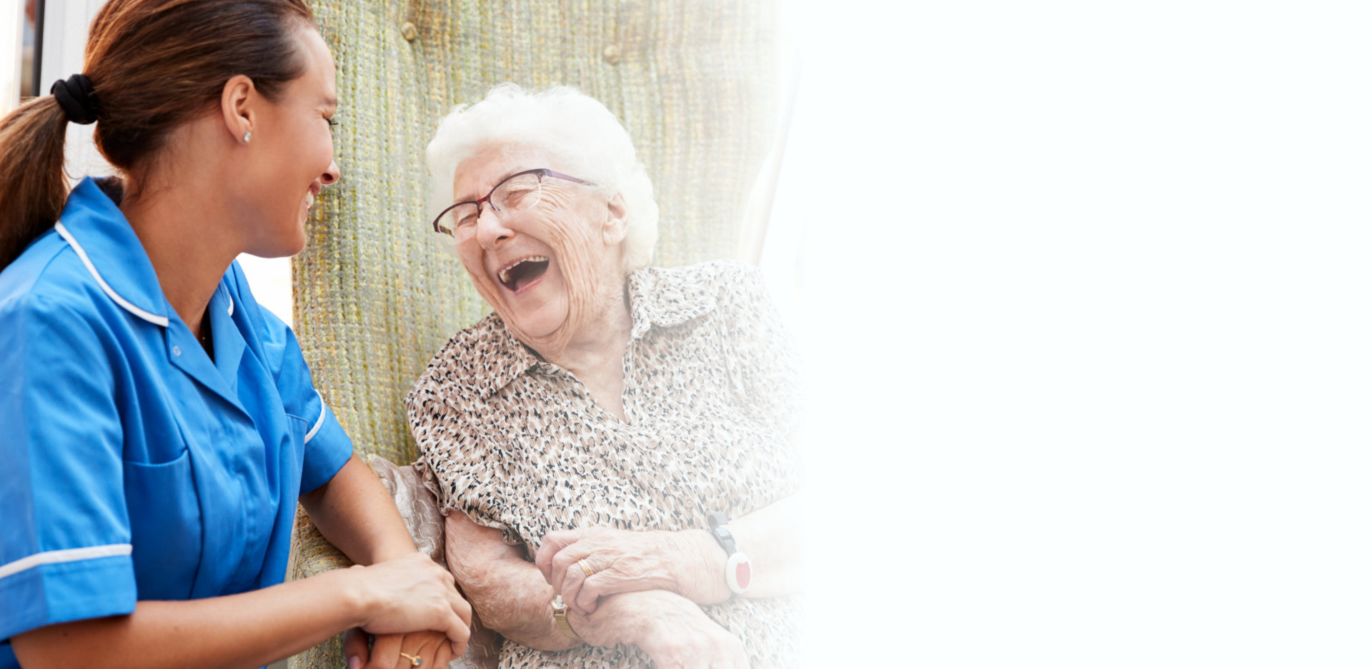 Senior Woman Sitting In Chair And Talking With Nurse