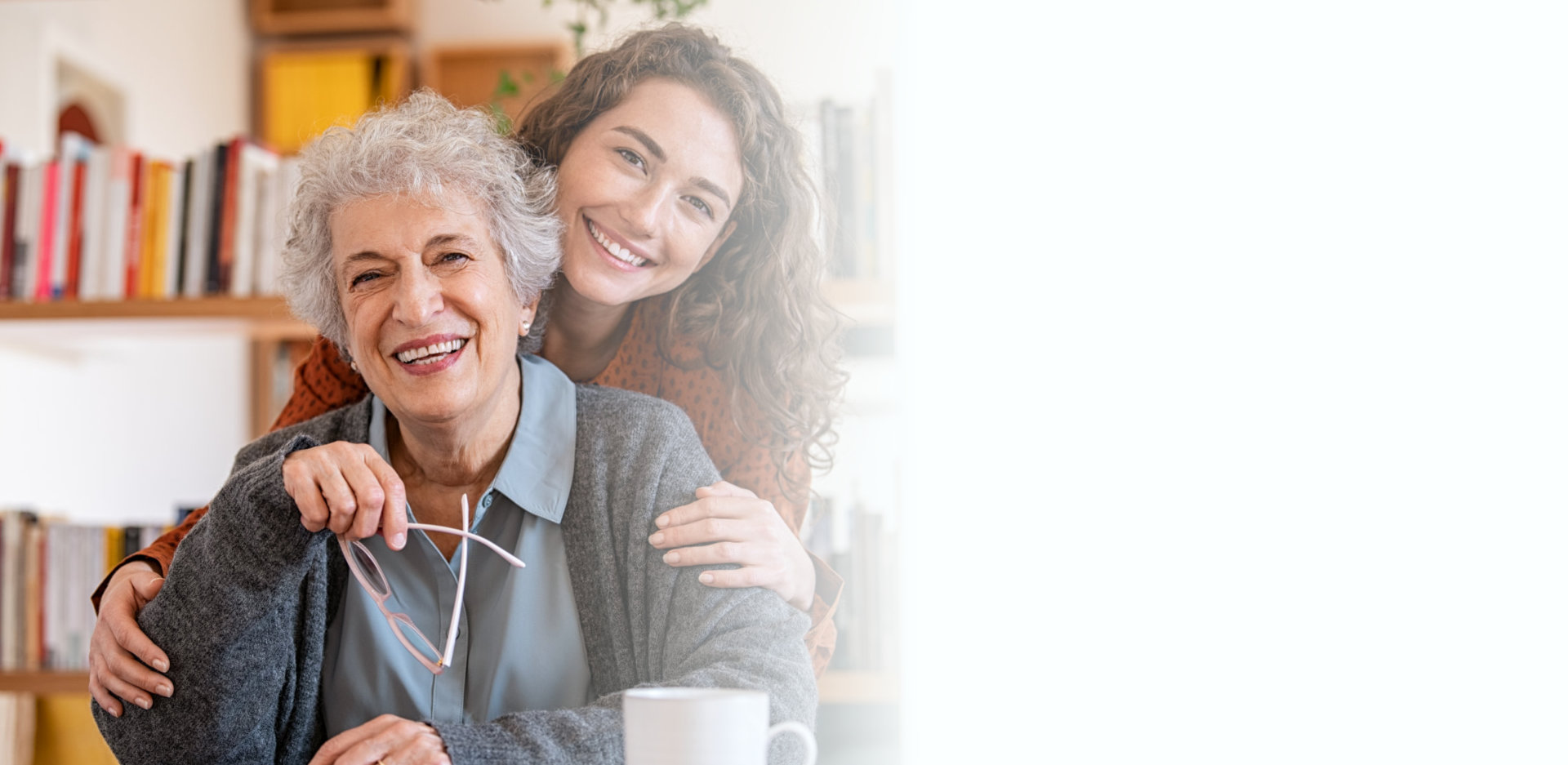 Young woman embracing senior mother at home